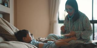快乐的妈妈和可爱的男孩在卧室里玩医生游戏。
