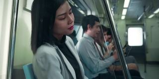 一个亚洲女人坐在地铁里。乘坐公共交通，她又累又沮丧