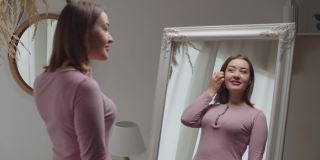 快乐美丽的成年女性在家中镜子前欣赏自己的容貌