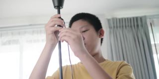亚洲男孩在家组装从网上买的新电灯，男孩自己打结。