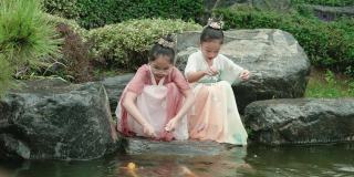 女孩们穿着汉服，在公园喂锦鲤。