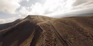 FPV无人机镜头:平稳稳定的飞行沿着山脉岩石山围绕高原湖。