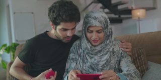 一对阿拉伯或中东夫妇正在手机上观看、欢呼和享受足球比赛