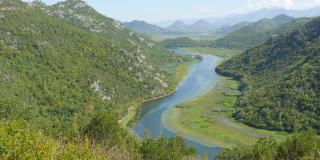 蓝色的河流穿过绿色的山谷，流向远方的群山。在黑山国家公园蜿蜒曲折的克诺耶维察河，蜿蜒穿过山间的沼泽，通往斯卡达湖
