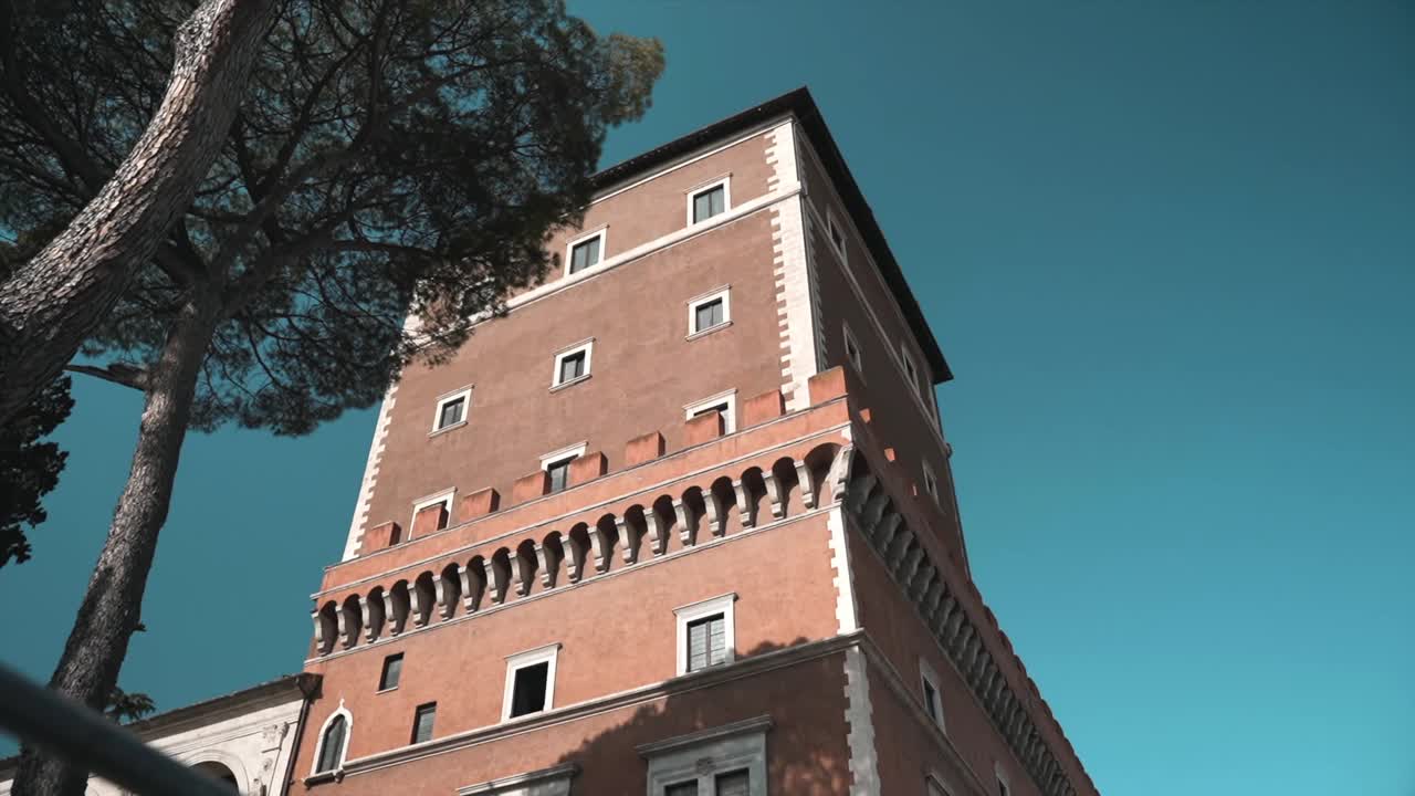 威尼斯宫著名塔在阳光下的低角度，惊人的蓝色狡猾的背景和生长的松树，罗马市中心特色罗马建筑立面的塔，意大利文化和建筑