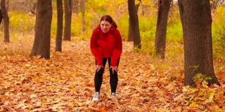 迷人的女运动员穿着鲜艳的运动服和运动鞋在秋天的公园跑步。训练和运动概念。