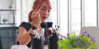 亚洲女性网红化妆师在家里用笔记本谈论化妆。