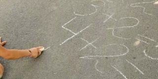孩子在柏油马路上写方程式。有选择性的重点。