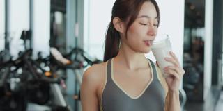 迷人的健身亚洲女性完成锻炼，并在训练后饮用蛋白质牛奶奶昔维生素。健身。健康的生活方式。