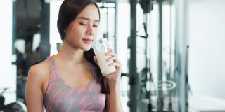 迷人的健身亚洲女性完成锻炼，并在训练后饮用蛋白质牛奶奶昔维生素。健身。健康的生活方式。