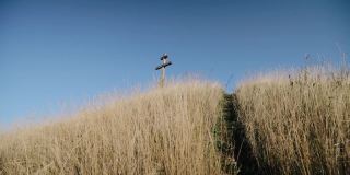 一个拿着相机的人爬上一座山上，山上有一个木十字架