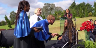 一名坐在轮椅上的大学生在毕业典礼上领取毕业证书