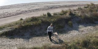 一个年轻的女人和她的狗在海滩上