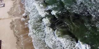 航拍无人机观察海浪翻滚到沙滩上的景象。