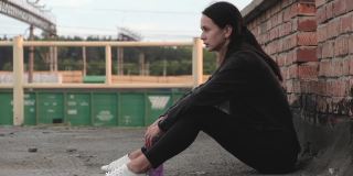 年轻的女运动员在训练后疲惫地坐在砖墙旁的屋顶上