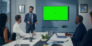办公室会议室会议介绍:成功商人谈话，使用绿屏色度键墙电视。成功向多民族投资者群体展示电子商务产品