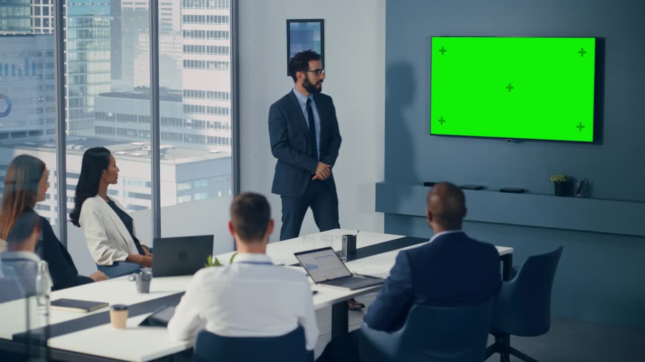 多元化办公室会议室会议:男项目经理利用绿屏色度键墙电视为投资团队呈现投资机会。电子商务产品策略。中宽