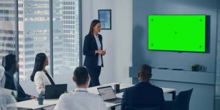 办公室会议室会议介绍:积极的商人谈话，使用绿色屏幕彩色键墙电视。成功向多民族投资者展示产品。广泛的静态照片