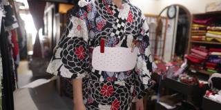 在出租和服商店里，一位日本妇女正在系宽腰带