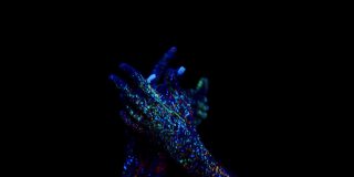 四只手涂上抽象的颜料，在荧光灯下做出富有美学魅力的流畅动作。特写镜头运动的手。概念的时尚艺术