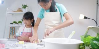 亚洲孩子在家里一起烤饼干前测量黄油，生活方式的概念。