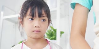 一个亚洲女孩看着她的姐姐量黄油，准备在家里一起烤饼干，生活方式的概念。