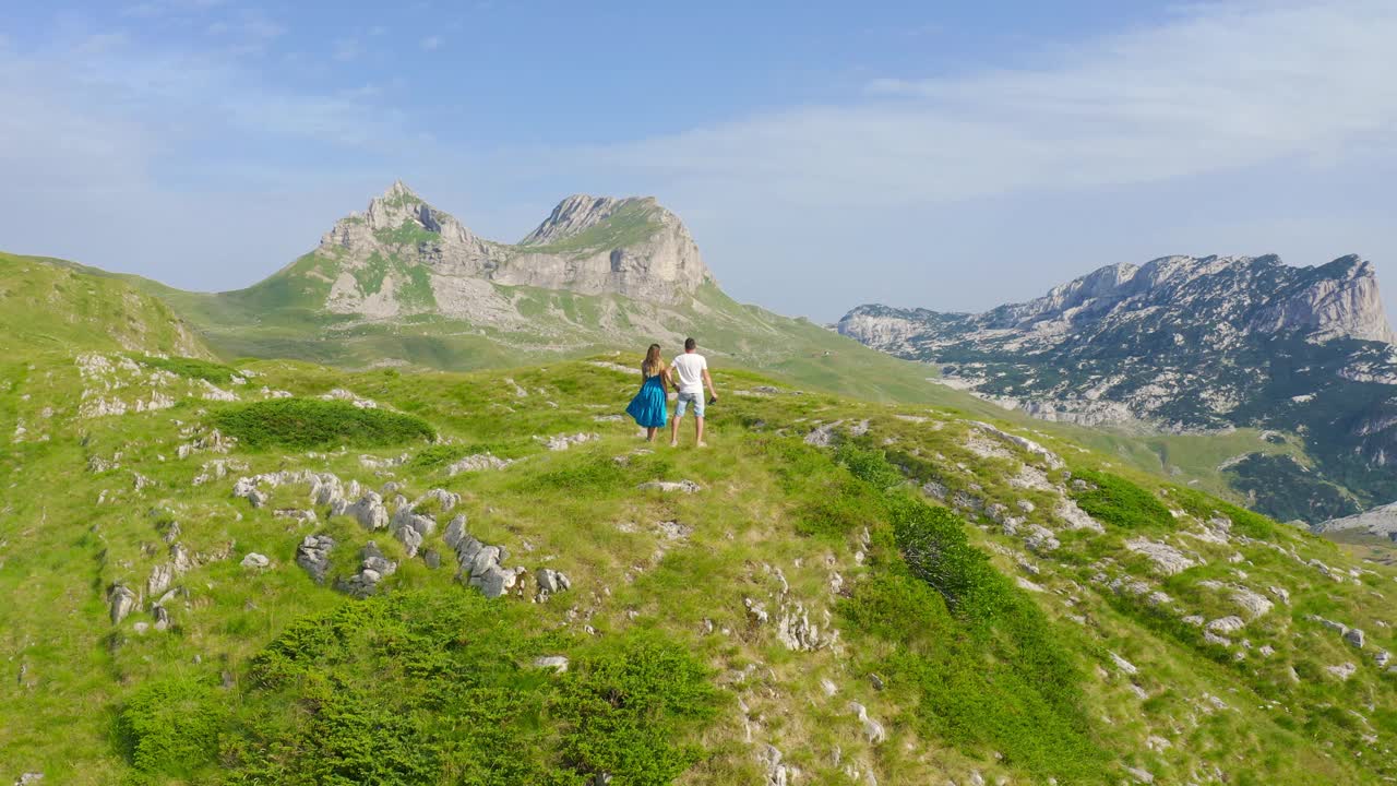 在黑山的杜米托，一对运动的年轻夫妇在他们活跃的春假期间在风景优美的山上徒步旅行。无人机视角4K。