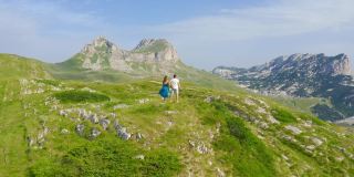 在黑山的杜米托，一对运动的年轻夫妇在他们活跃的春假期间在风景优美的山上徒步旅行。无人机视角4K。