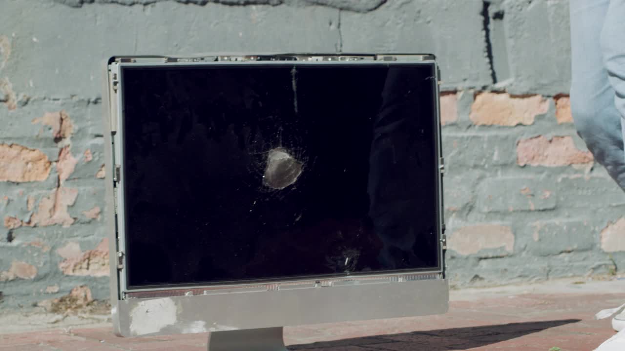 一段4k视频显示，一名面目模糊的男子在外面用大锤砸电脑
