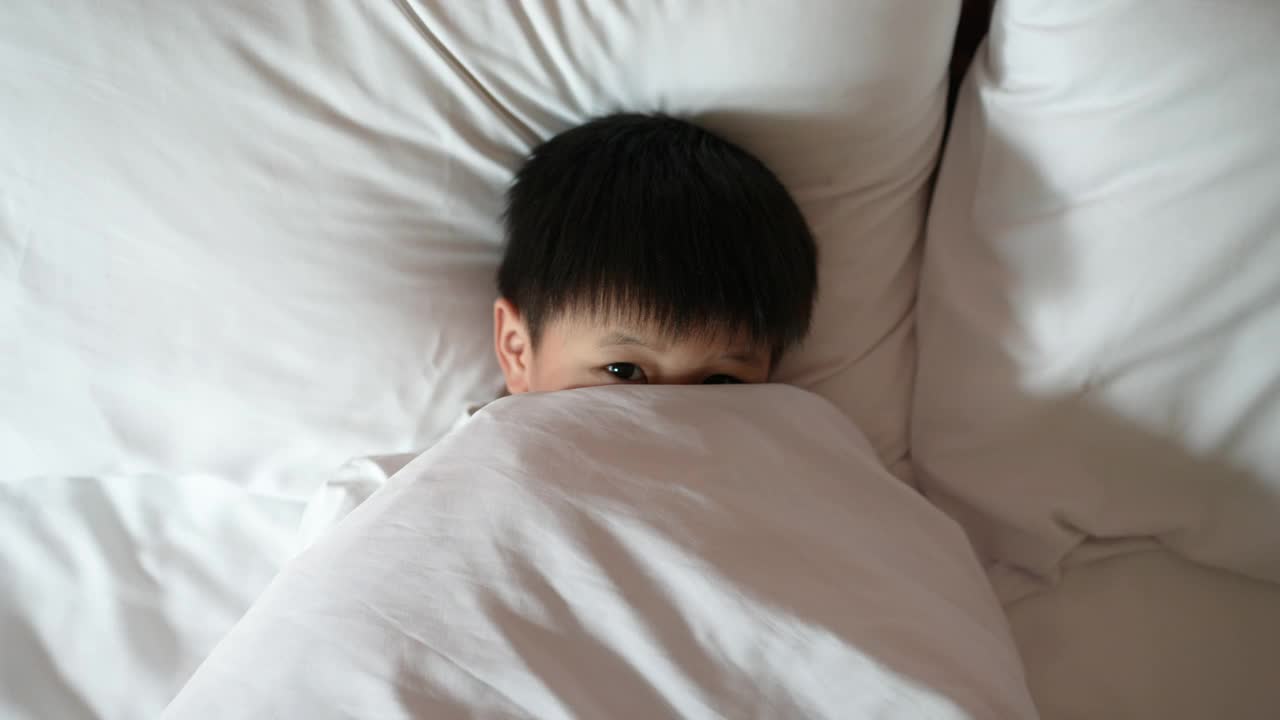 亚洲男孩在卧室里醒来玩躲猫猫