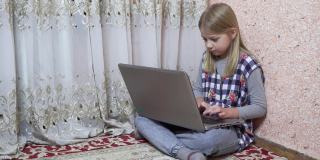 一个小女孩坐在她房间的地板上，一边看书一边用笔记本电脑。家庭教育。