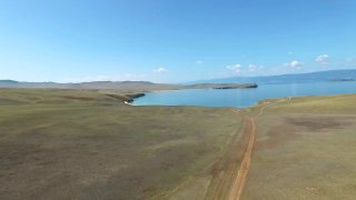鸟瞰图的泥路到蓝色的水海岸在阳光明媚的日子，奥尔洪，贝加尔湖视频素材模板下载