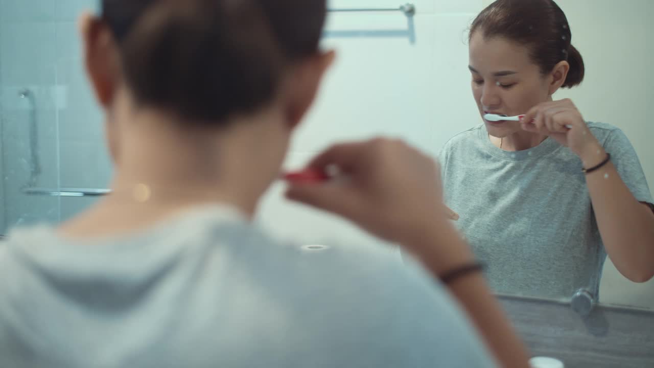 女人在浴室里刷牙和使用智能手机