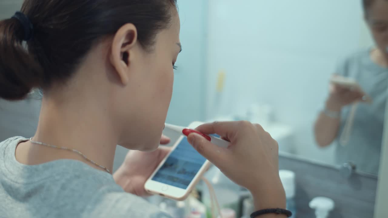 女性在浴室刷牙和使用智能手机，跟踪拍摄