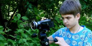 小男孩带着摄像机拍摄关于公园自然背景的影片。
