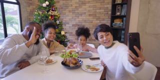 在庆祝节日聚会期间，一家人一起用手机视频通话，享受圣诞大餐的中景