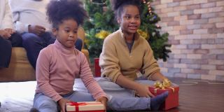 两个女儿在一起享受圣诞节或新年假期时，用礼物盒给她的妈妈和爸爸一个惊喜