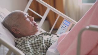 亚洲华人老年男性患者因疼痛躺在医院病房卧床休息视频素材模板下载