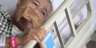 亚洲华人老年男性患者因疼痛躺在医院病房卧床休息