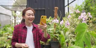 4K亚洲女植物商店老板在智能手机上直播盆栽为在线商店