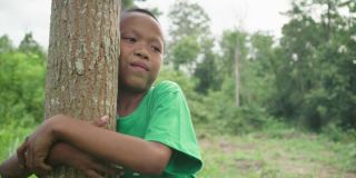 森林里的孩子拥抱着树。地球日。