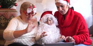 一家人戴着红色的圣诞帽和滑稽的眼镜，开着视频会议