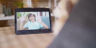视频打电话给家庭社会距离概念，亚洲女性手势和问候她的儿子爱和幸福的谈话从平板电脑上与小狗朋友在线交谈