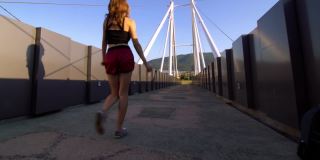 女孩在一座现代化的人行桥上行走、旋转和跳舞