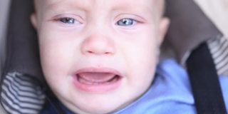 特写婴儿啼哭婴儿大蓝眼睛乳牙。初期的概念