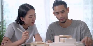 男人和女人规划一个模型概念设计。夫妻夫妻看纸堆模型。人们计划建设建筑住宅。建筑师谈论房子项目。