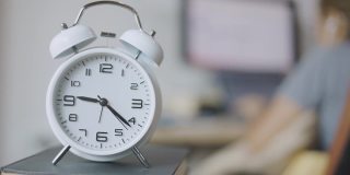 时间流逝的时钟快速移动在早上的工作高峰时间，商业妇女工作在电脑和她的办公桌在家里显示出与时间竞争的压力忙碌工作的概念。