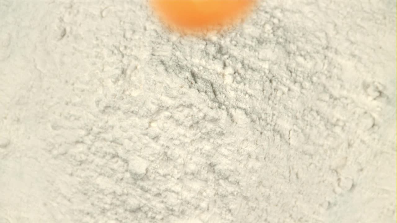 超级慢动作新鲜鸡蛋落入面粉中。用高速摄像机以每秒1000帧的速度拍摄。