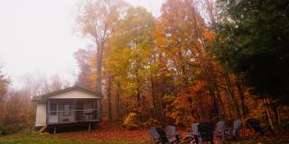 时光流逝:秋天，明亮的橙色树叶悬挂在一座老式房屋的屋顶前。