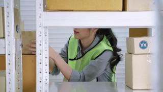 亚洲女工在仓库分拣箱子到仓库货架，储存和分配的概念。视频素材模板下载